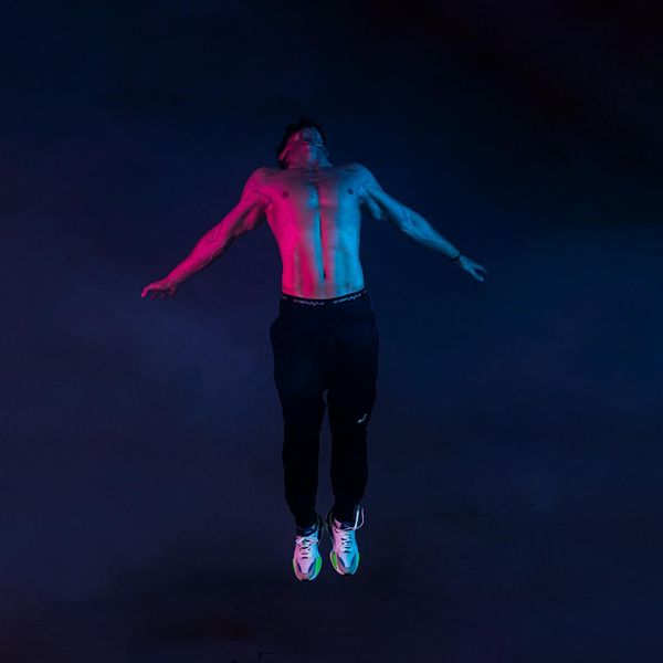 Person in a dynamic yoga pose, radiating energy, set against a dark, minimalist background.